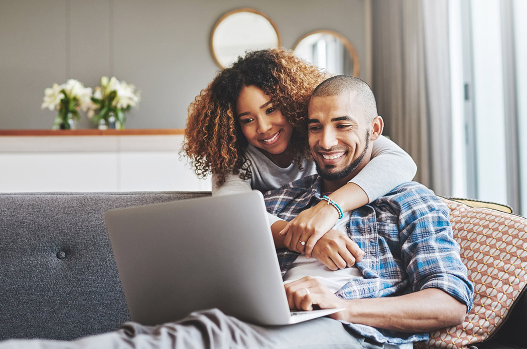 young couple sitting on couch and looking at a laptop