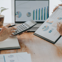 Person holding calculator and another person holding financial report conferring