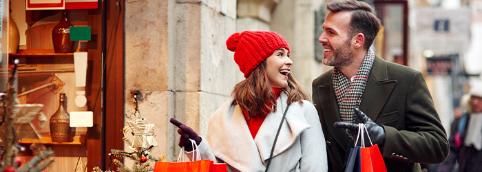 Man and woman smiling at each other and shopping outside during the winter holidays