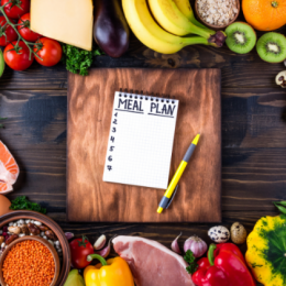 Meal Planning written on notepad with fruits, vegetables and meats displayed around it