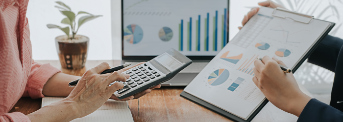 Person holding calculator and another person holding financial report conferring