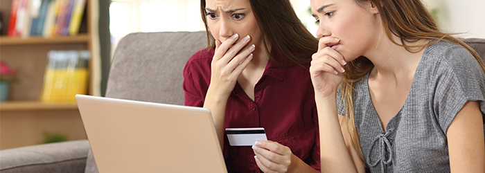 Two women looking concerned at the laptop and holding a credit card