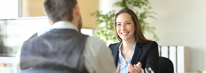 Woman dressed in business casual clothing gesturing and smiling at man