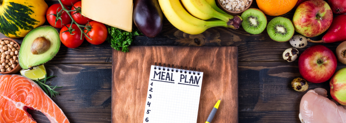 Meal Planning written on notepad with fruits, vegetables and meats displayed around it