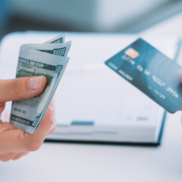 Person holding cash out in hand and person holding credit card out in hand