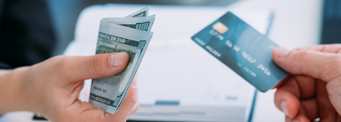 Person holding cash out in hand and person holding credit card out in hand